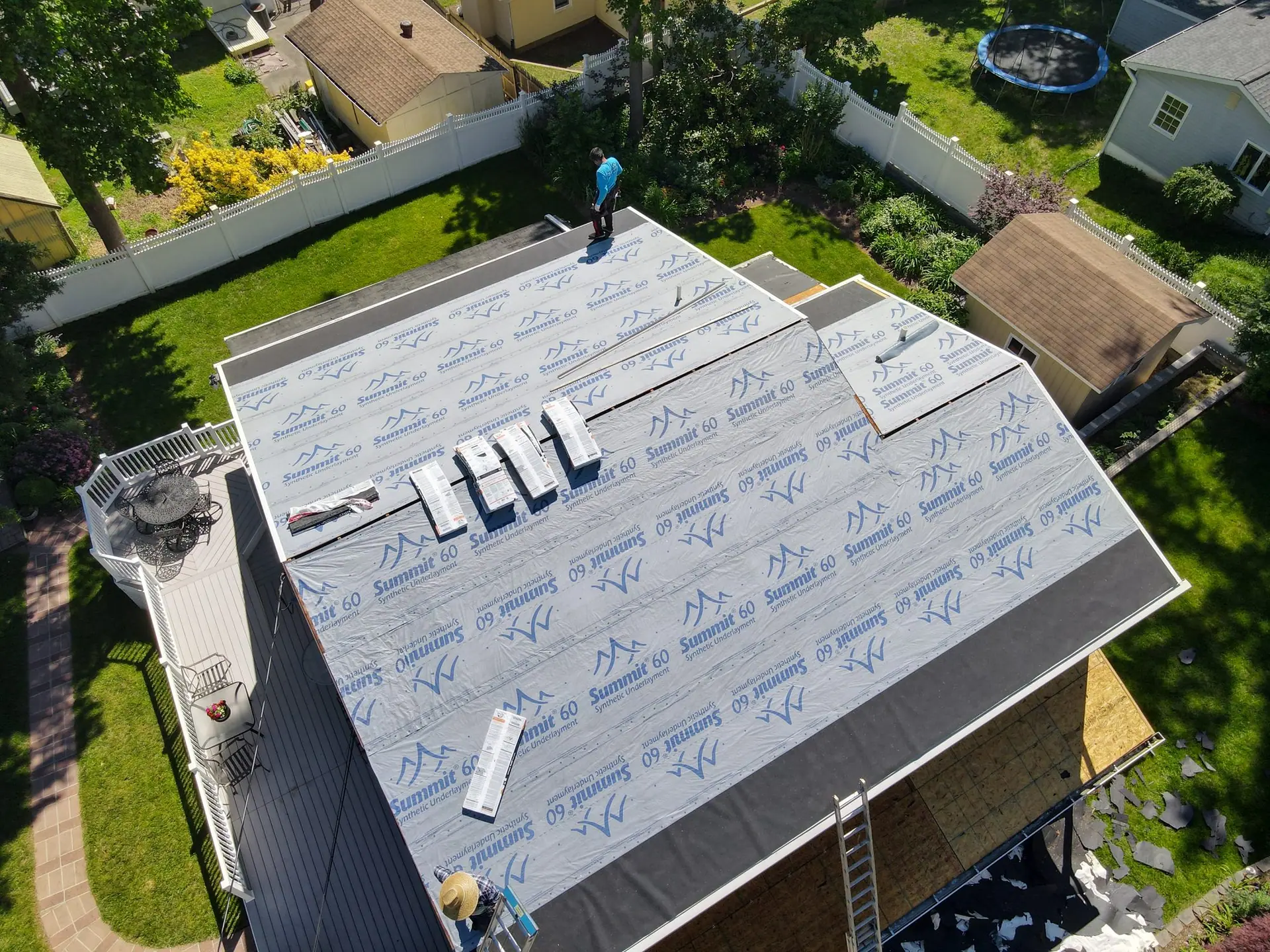 Aerial view of a Pineda's Roofing crew installing Atlas Summit 60 synthetic underlayment on a home