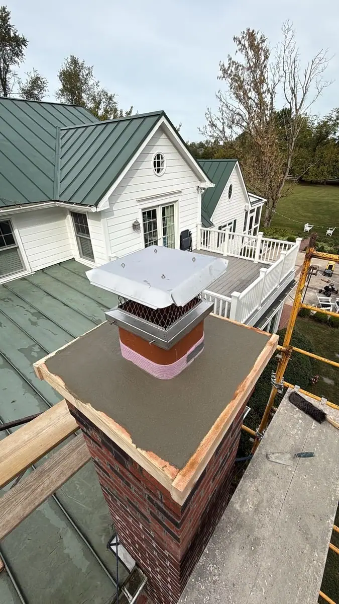 New chimney crown, wood form still in place, with a stainless steel chimney cap