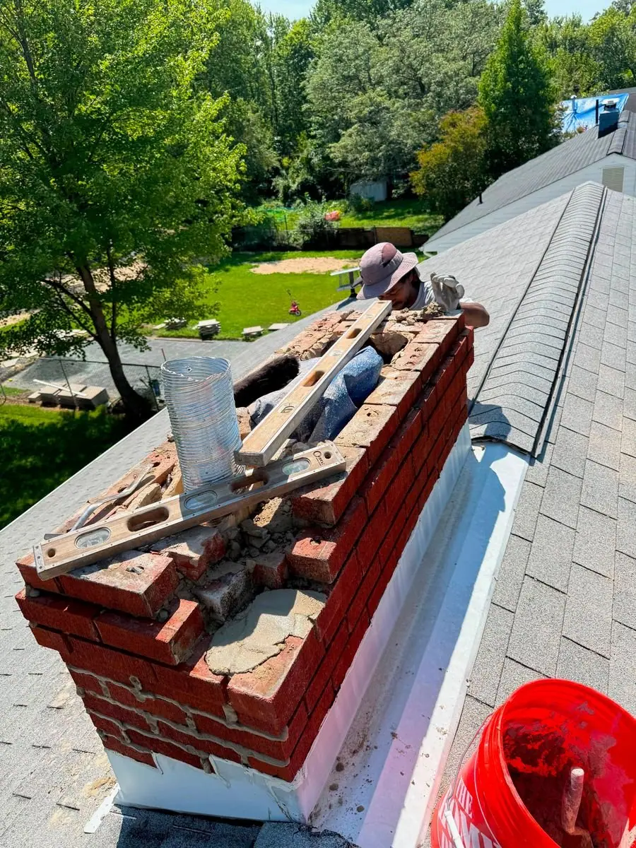 Pineda's Roofing mason rebuilding the top of a brick chimney before the new crown