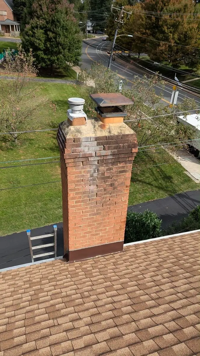 Weathered brick chimney with stained, crumbling mortar and an old crown before repair