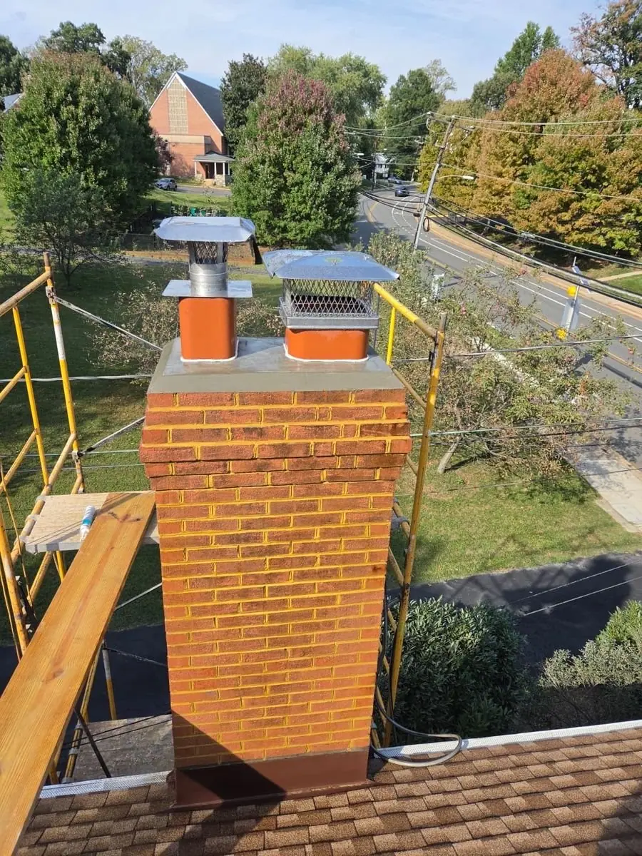 Repointed brick chimney with a new crown and two chimney caps